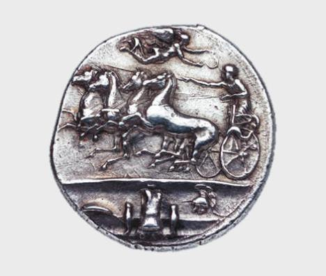 Αργυρό δεκάδραχμον Συρακουσών, αρχές 4ου αι. π.Χ. Νομισματικό Μουσείο, Αθήνα. Η Νίκη υπερίπταται των αλόγων και στεφανώνει τον ηνίοχο του τεθρίππου. Στο έξεργο απεικονίζεται αμυντικός οπλισμός δηλ. ασπίδα, θώρακας, περικνημίδες και περικεφαλαία. Τα όπλα περιγράφονται ως «ΑΘΛΑ» ένας όρος που θα μπορούσε να ερμηνευθεί ως βραβεία κάποιου αγώνα ή πολεμικά τρόπαια.